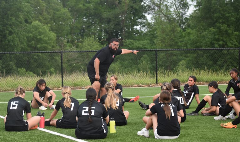 After leading the Marshall Lady Owls’ soccer team to a 17-5 mark this past season, first-year head coach Duglas Lopez (standing) was chosen the Select Brand Coach of the Year. The lady Owls finished second in the North Central Missouri Conference with an 8-2 mark. (File Photo - Hobby King/Democrat-News)