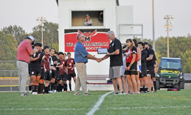 Marshall head coach Justin Van Winkle (right) is presented the award as the “Coach of the Year” for the entire state of Missouri in the sport of soccer by assistant executive director of boys’ soccer at the Missouri State High School Activities Association Marty Marsh Monday night. (Sarah Gray/Democrat-News)