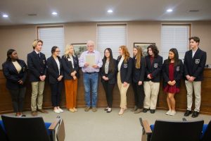 Marshall Mayor Vince Lutterbie reads a proclamation deeming November as Distributive Education Clubs of America (DECA) Month for the Saline County Career Center. DECA students gathered in the Marshall City Council Chambers on Wednesday afternoon, Nov. 1, and talked about their projects. Pictured left to right are: KiAsiah Harris; Jackson Russell; Avery Evans; Bailey Kueker; Lutterbie; Michelle Lin; Holly Huston; Peyton Marshall; Kolten Gotmer; Kaylen Alvarez; and Ethan Russell. Danielle Linton-Hatfield/Democrat-News